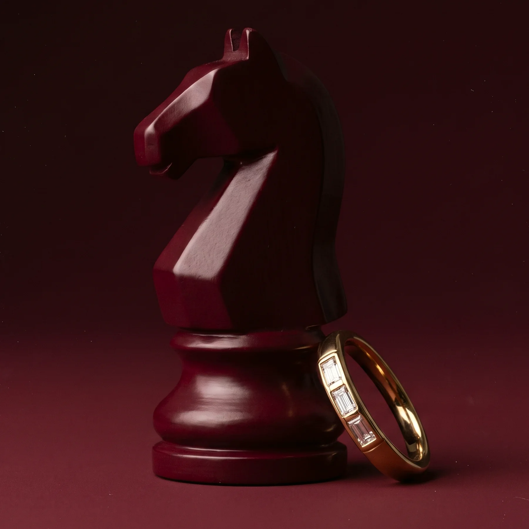 The family baguette ring photographed beside a burgundy chess knight.