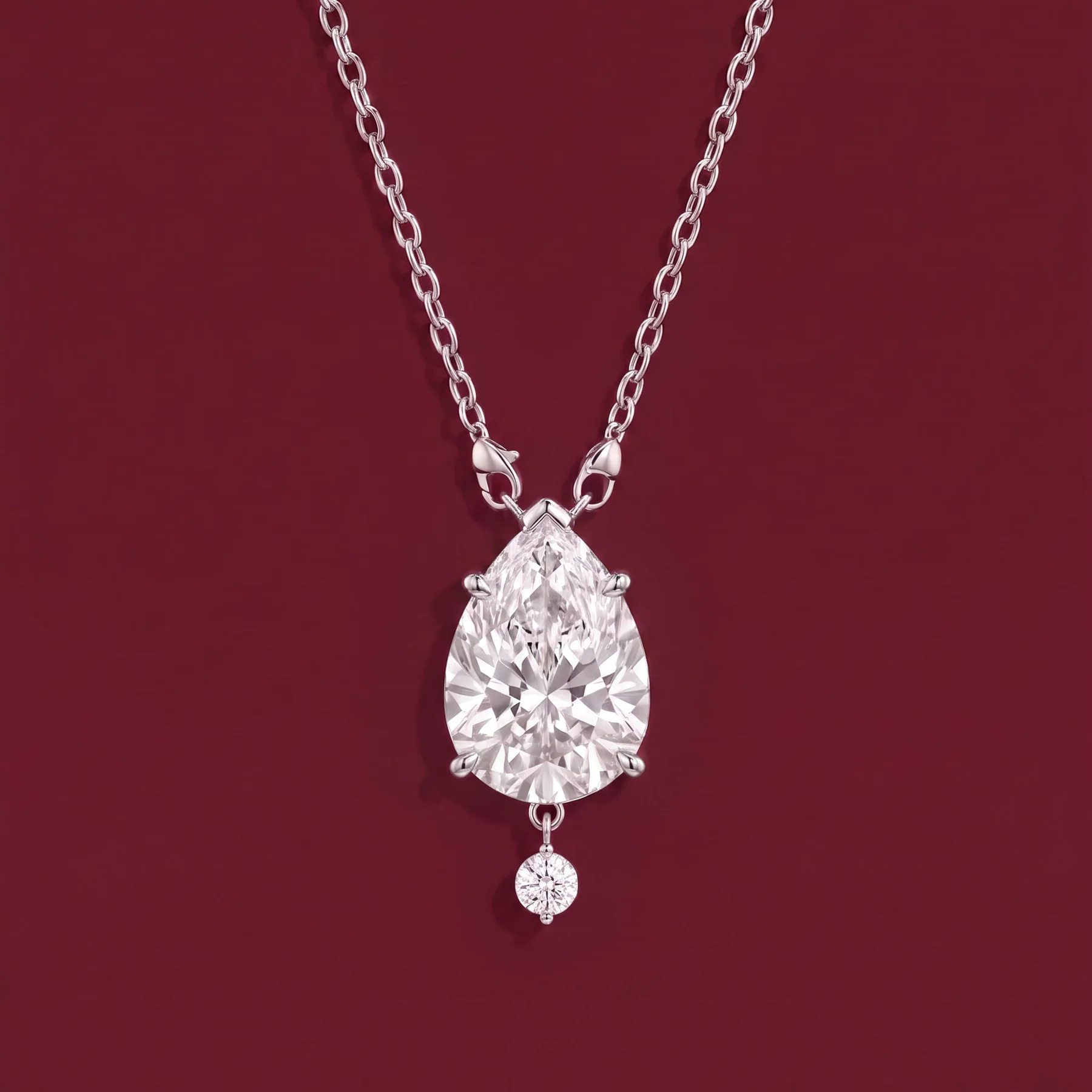 A pear-shaped family diamond pendant on burgundy velvet.